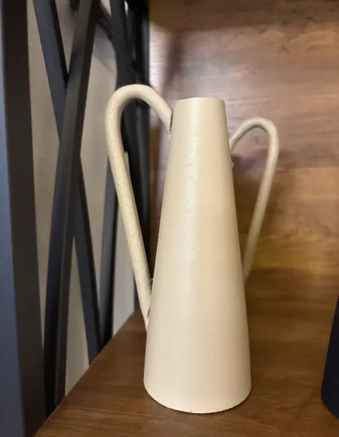 Cremefarbene Vase mit zwei Henkeln und rauer Oberfläche im Deko-Regal