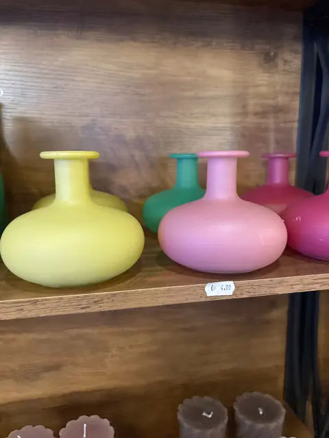Bauchige Vasen in Gelb, Rosa, Türkis und Pink im Deko-Regal, darunter Kerzen
