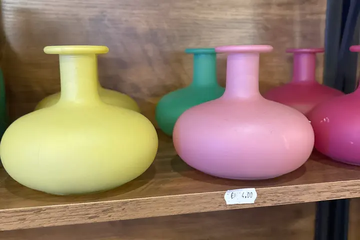 Bauchige Vasen in Gelb, Rosa, Türkis und Pink im Deko-Regal, darunter Kerzen