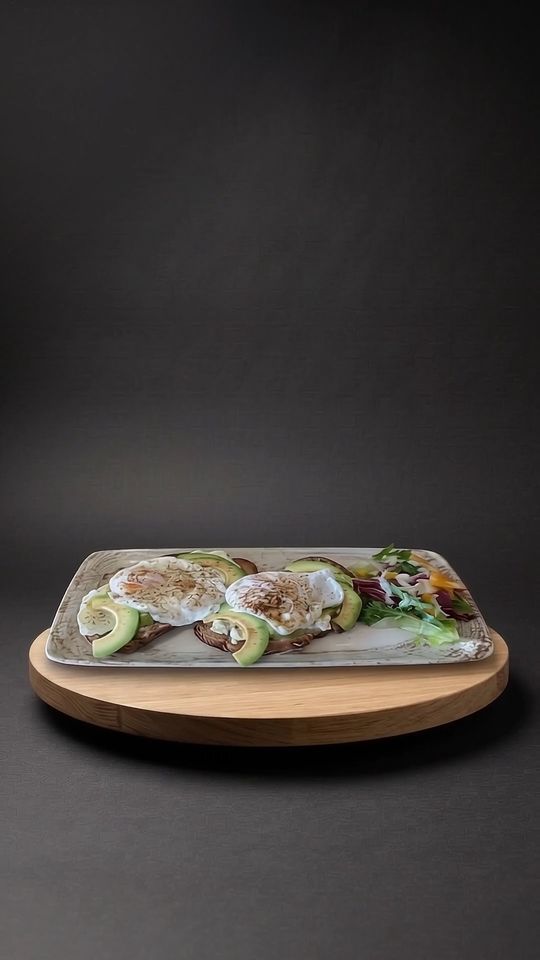 Avocado Toast auf einer Eichenplatte vor dunklem Hintergrund