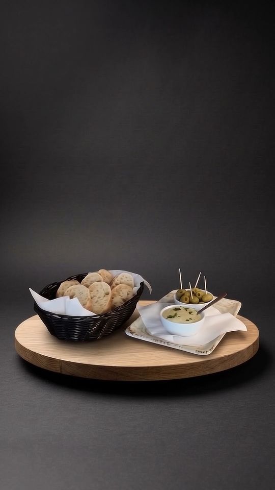 Baguette mit Aioli auf einer Eichenplatte vor dunklem Hintergrund