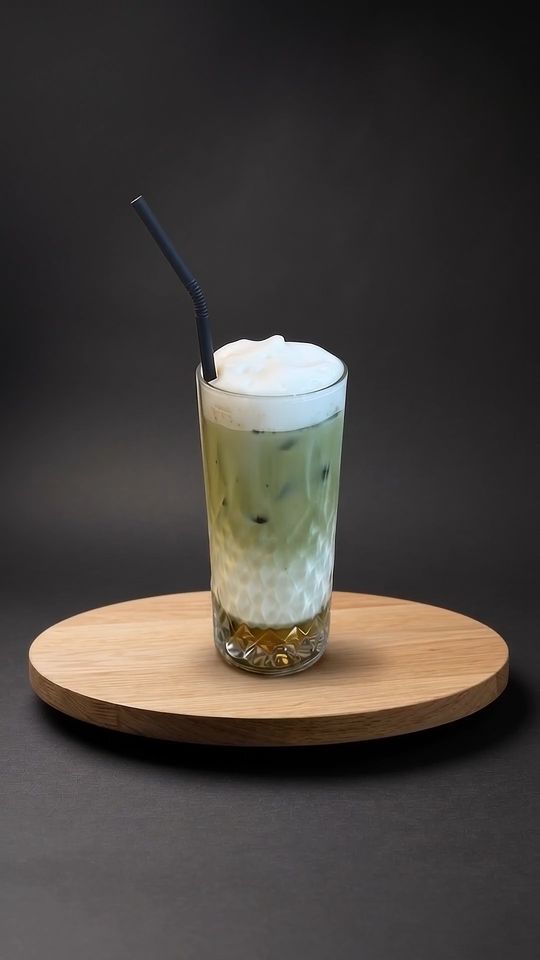 Iced Matcha Latte auf einer Eichenplatte vor dunklem Hintergrund